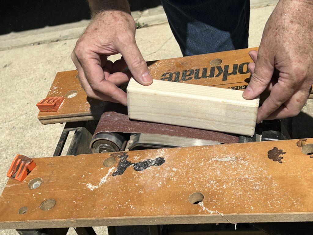 Sanding a Jenga block with a belt sander