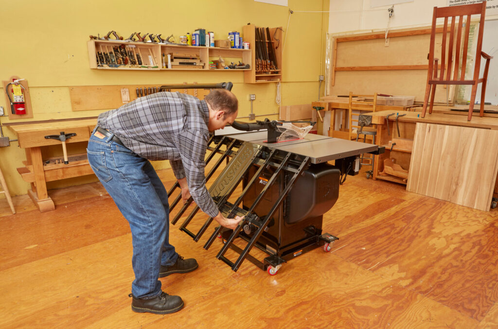 Woodworker lifts and engages the SawStop Folding Outfeed Table