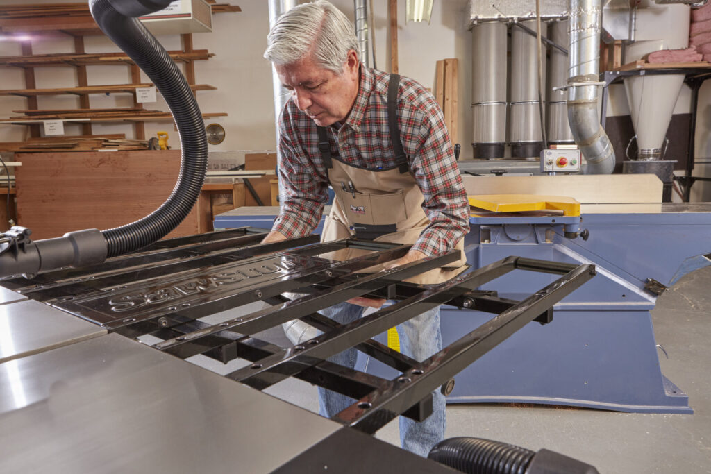 Woodworker lifts and engages the SawStop Folding Outfeed Table